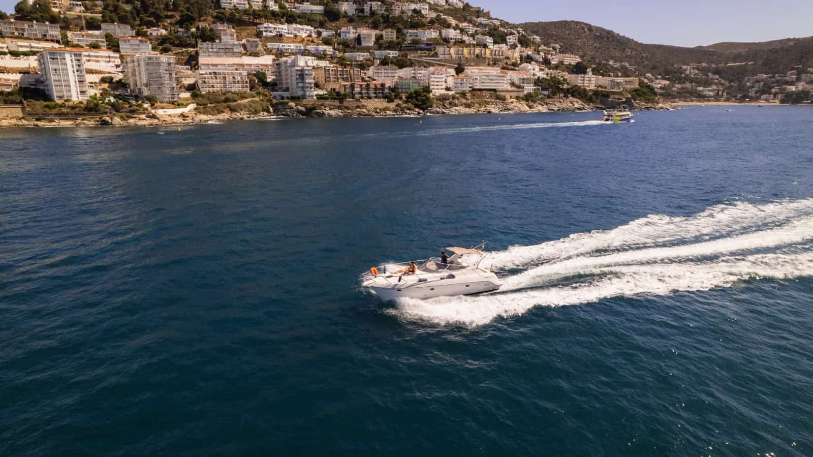 Excursión en barco navegando frente al paseo marítimo de Roses, Costa Brava
